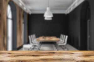 Modern meeting room interior with black walls, tiled floor and long wooden table with white chairs. A mental health counselor is preparing for a therapy workshop in Indianapolis, IN at Northside Mental Health