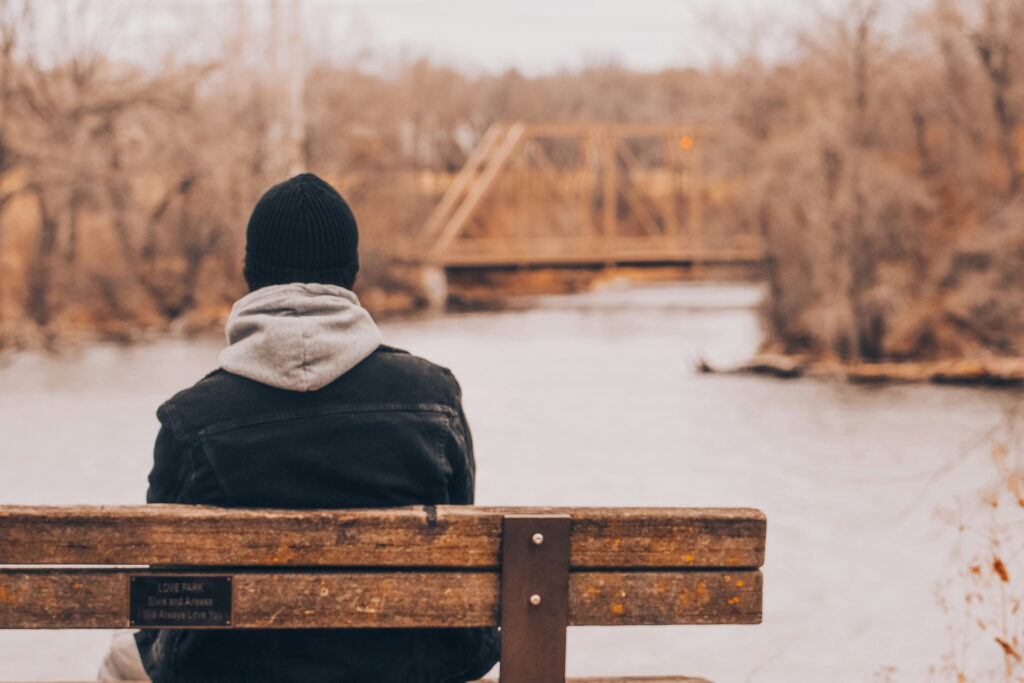 A man sitting on a bench overlooking a river