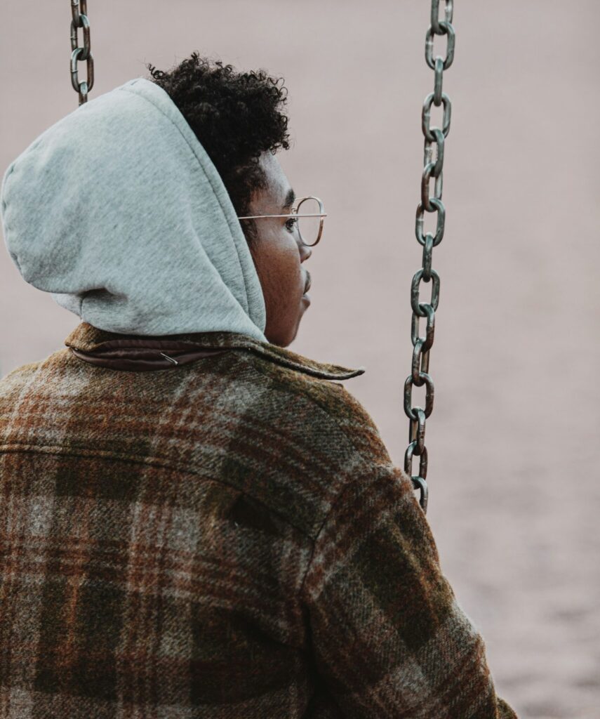 Man sitting on swing looking off into the distance