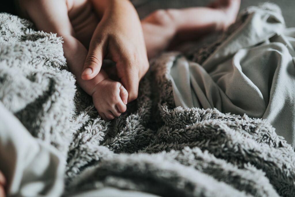 An adult holding an infant's hand